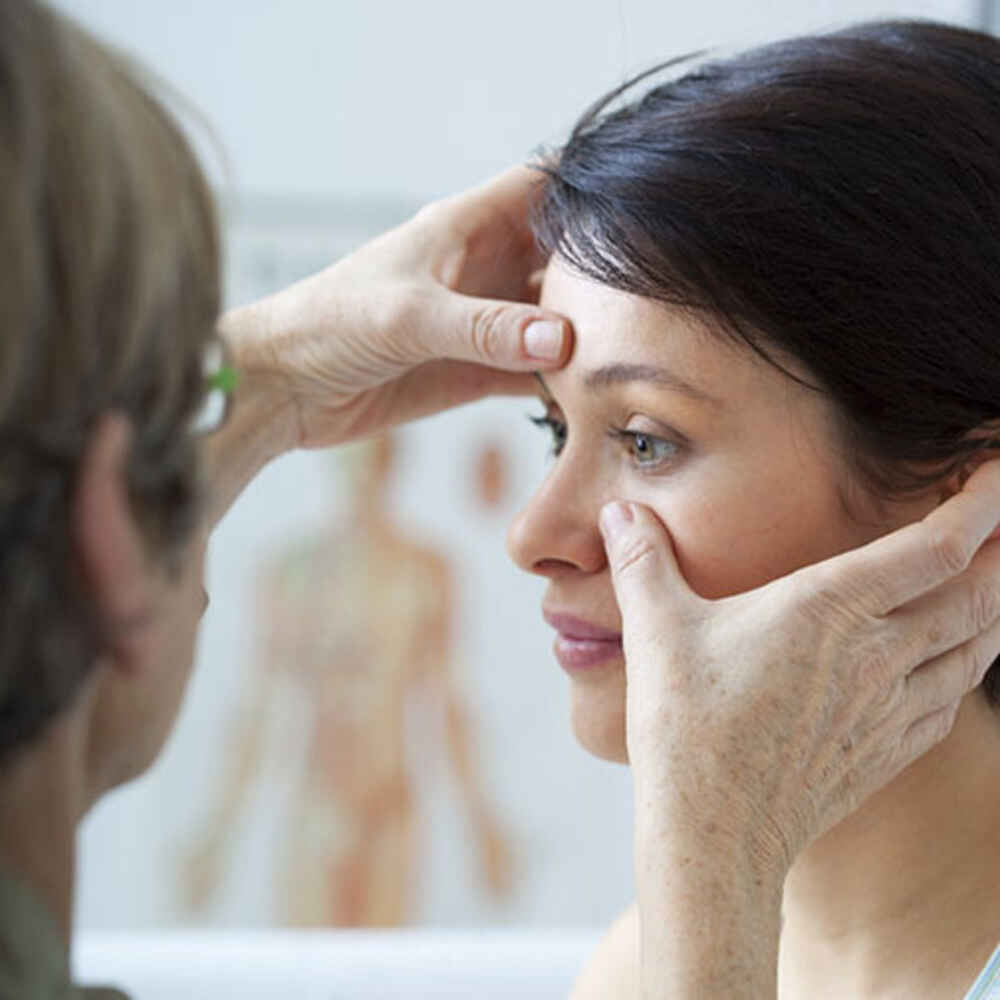Doctor pressing against patient's face to check for nasal or sinus issues