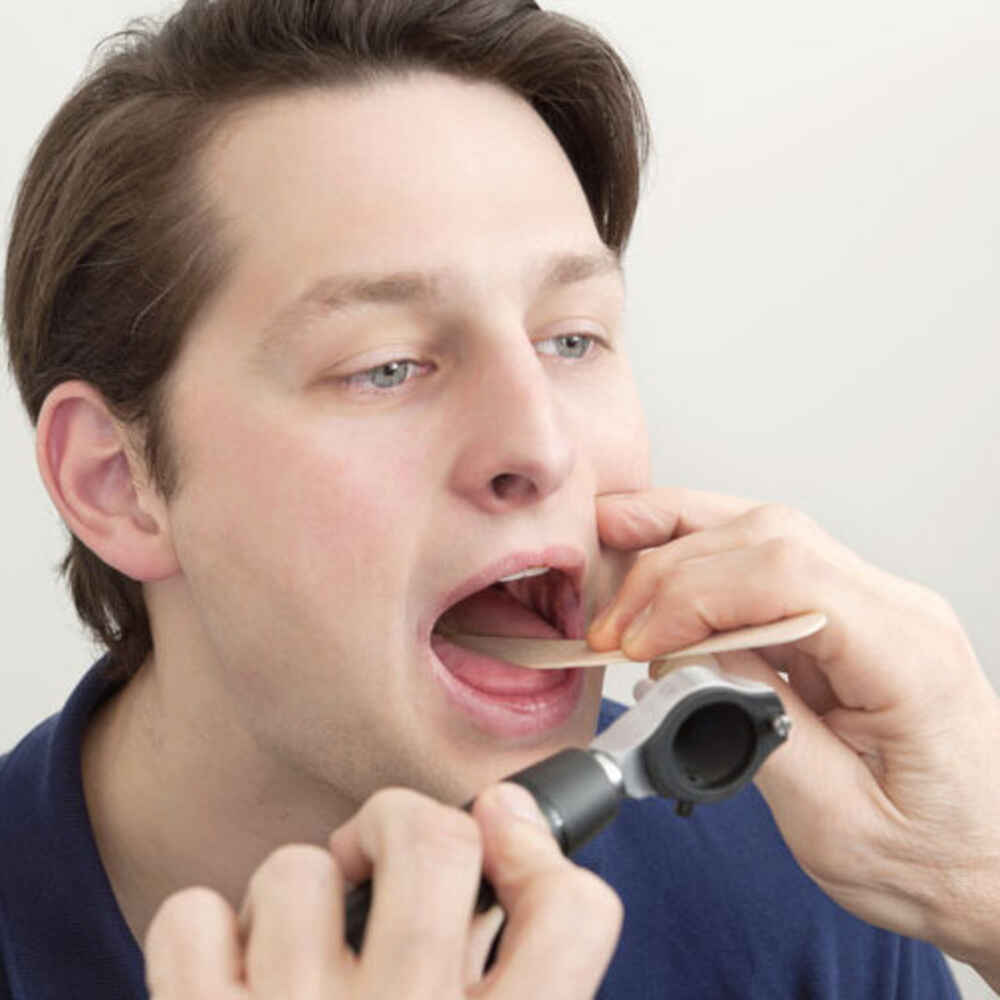 Doctor checking inside patient's mouth for oral issues