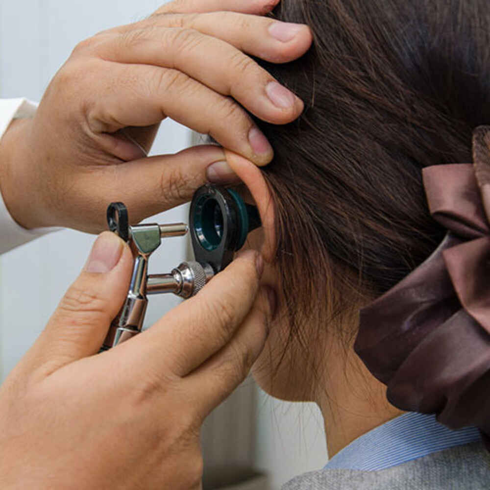 Doctor checking patient's ear for earwax buildup