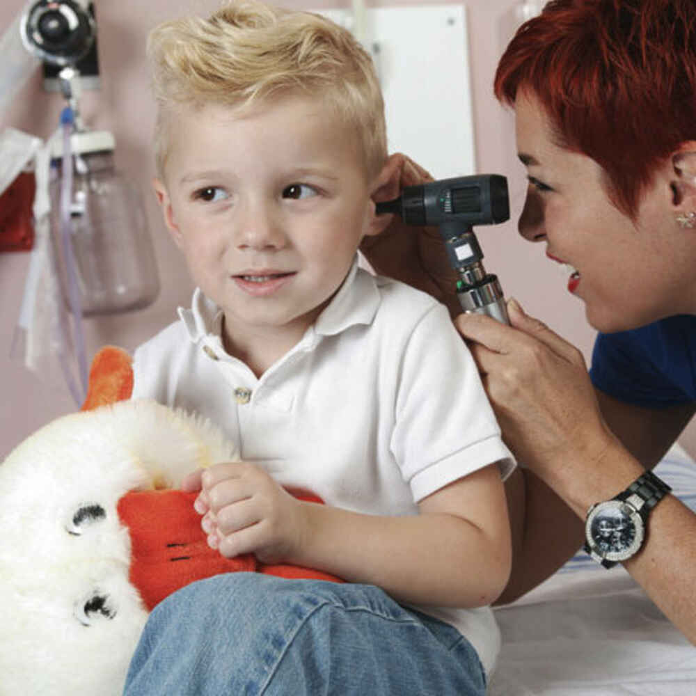 Doctor checking pediatric patient's ear for earwax buildup